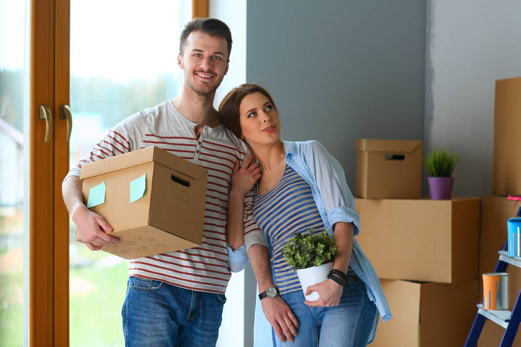 Felice giovane coppia disimballaggio o scatole di imballaggio e trasferirsi in una nuova casa
 - Foto, immagini