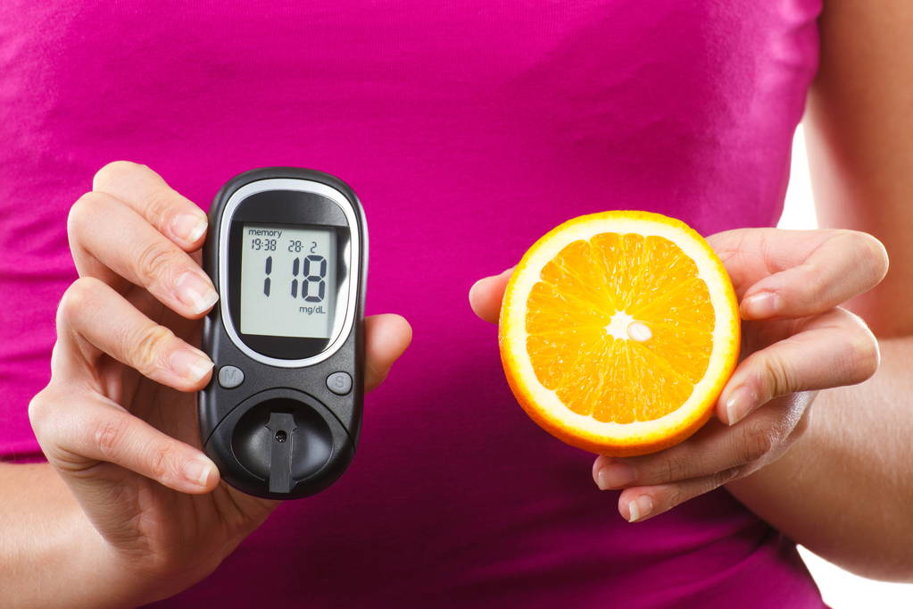 Ruka držící glukometr a čerstvý pomeranč, měření a kontroly cukru koncept úrovně, diabetes - Fotografie, Obrázek