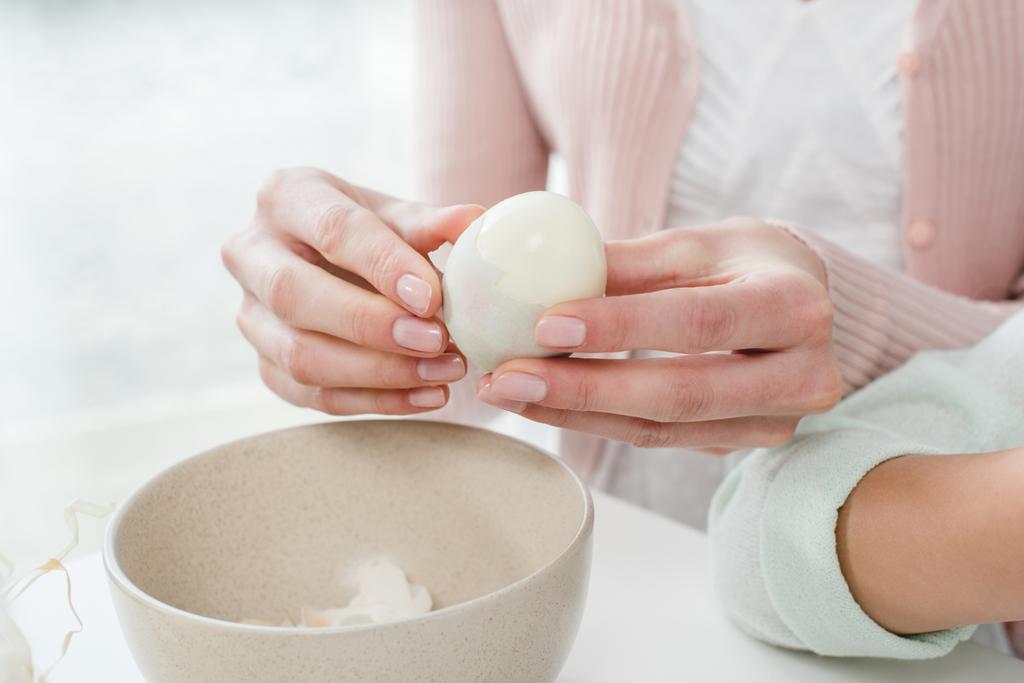 Vrouw peeling gekookt ei  - Foto, afbeelding