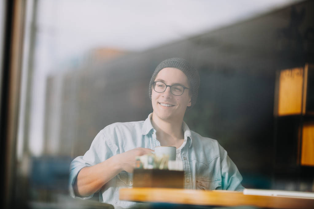 Красивий бізнесмен у повсякденному одязі та окулярах використовує ноутбук у кафе
 - Фото, зображення