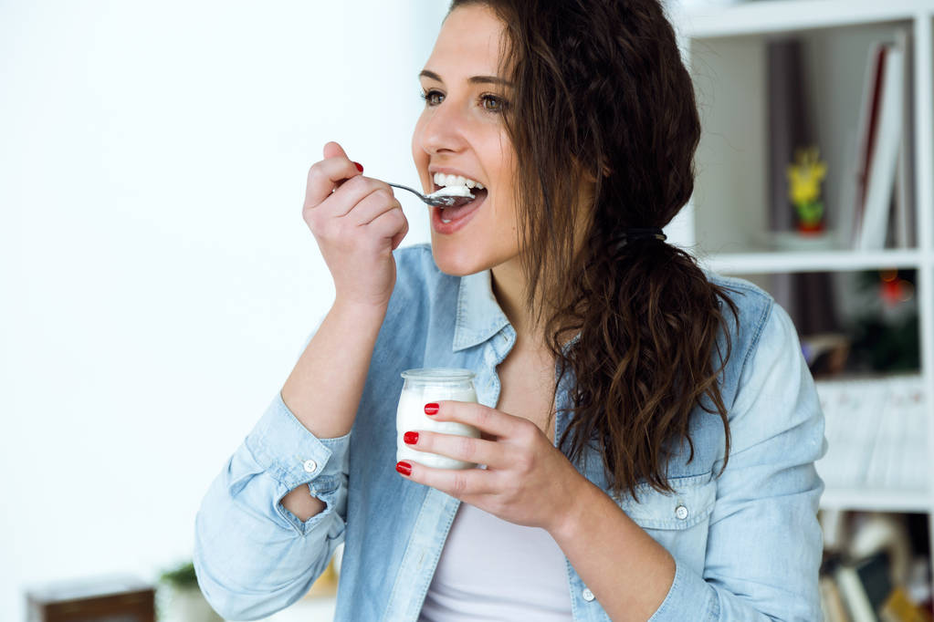 Belle jeune femme mangeant du yaourt à la maison
. - Photo, image