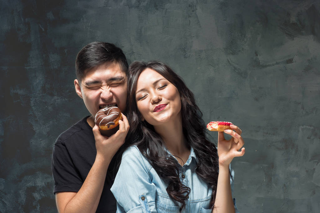 Młode Azjatki pary zajadać z słodkie kolorowe pączek - Zdjęcie, obraz
