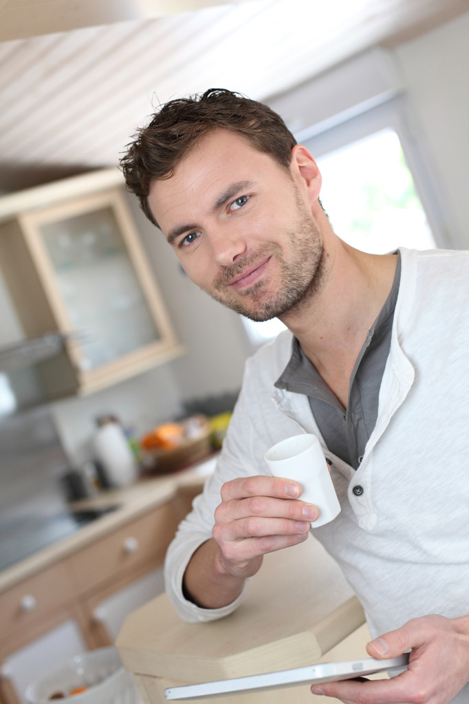 Segítségével elektronikus tabletta, miközben a kávéfogyasztás, fiatal férfi - Fotó, kép