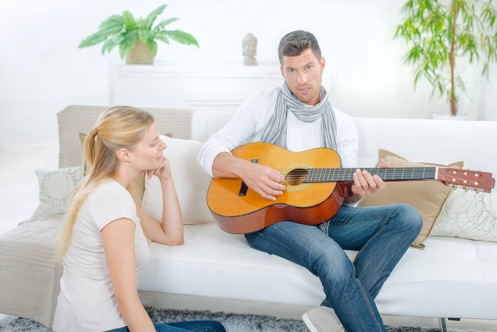 Probeert te imponeren zijn vriendin door het spelen van gitaar - Foto, afbeelding