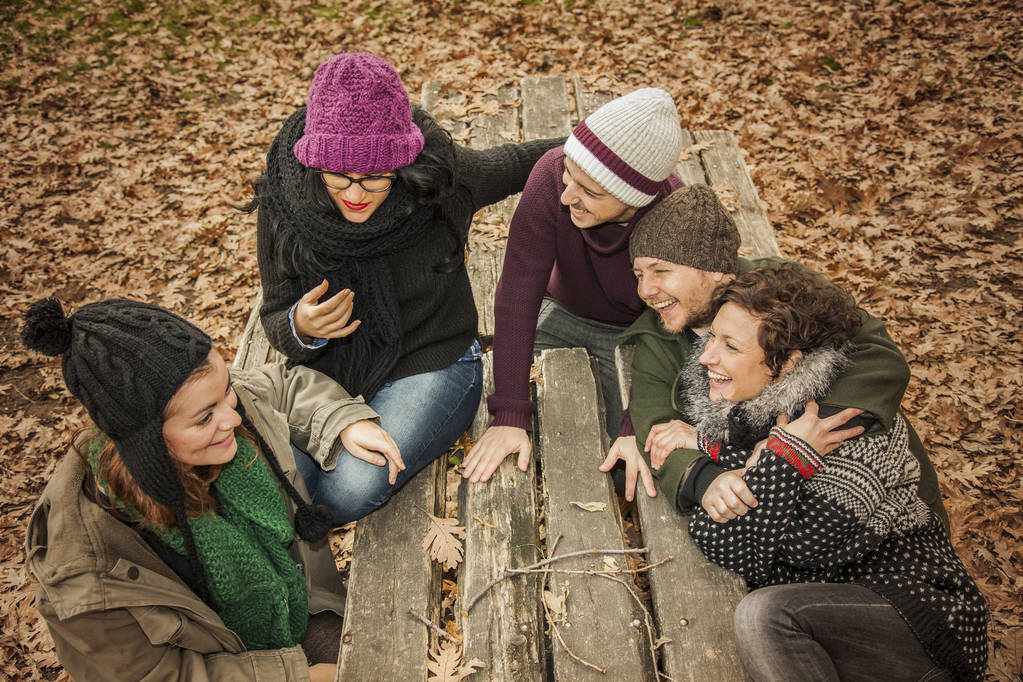 Conversating φίλοι και το γέλιο σε ένα πάρκο γεμάτο φύλλα. Autu - Φωτογραφία, εικόνα