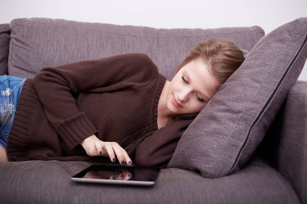 щаслива молода жінка з планшетним ПК, що лежить на дивані
 - Фото, зображення