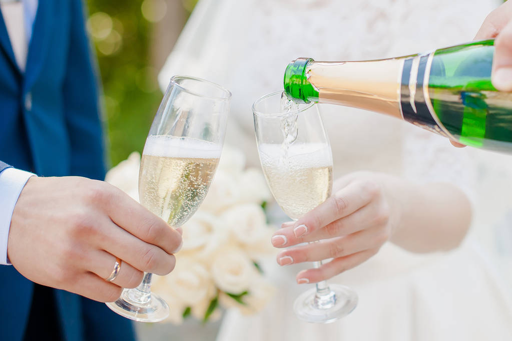 bruid en bruidegom in het park met champagne - Foto, afbeelding