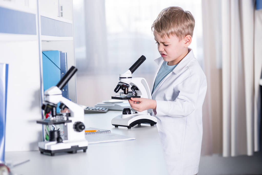 Маленький хлопчик використовує мікроскоп
 - Фото, зображення