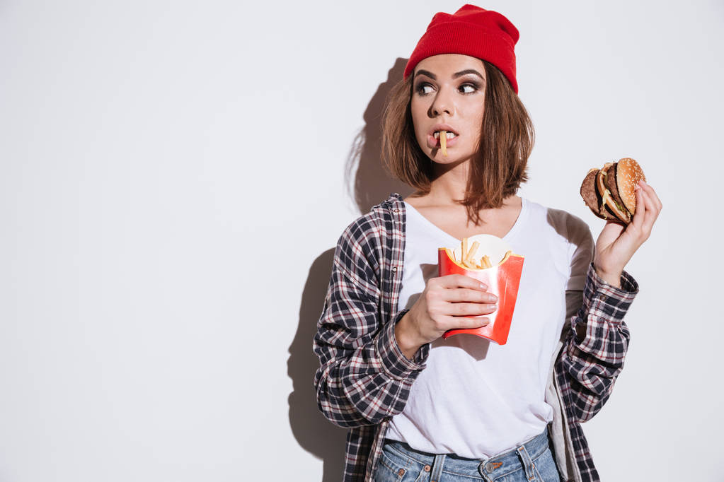 Femme confuse affamée avec hamburger et frites
 - Photo, image