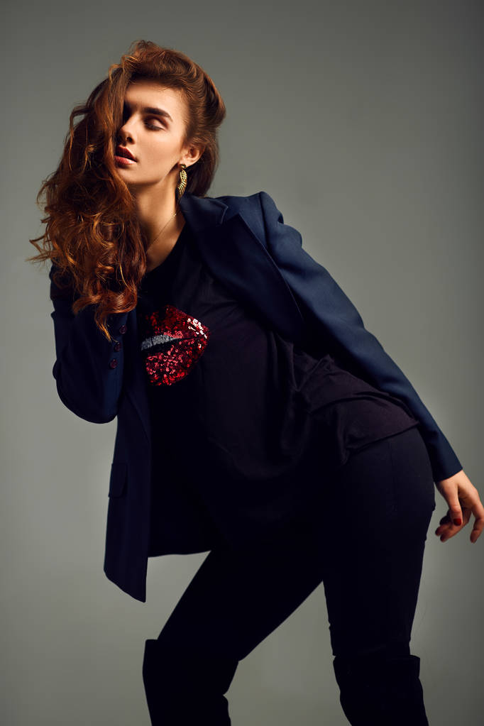 menina bonita vestindo uma jaqueta, camisa e calças posando em um fundo cinza. foto do estúdio
. - Foto, Imagem
