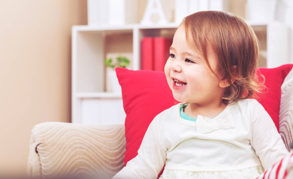 Маленькая девочка смеется в своей гостиной
 - Фото, изображение
