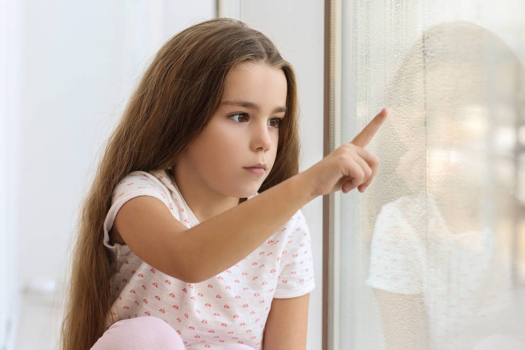 Triste niña dibujando en vidrio de ventana en casa
 - Foto, imagen