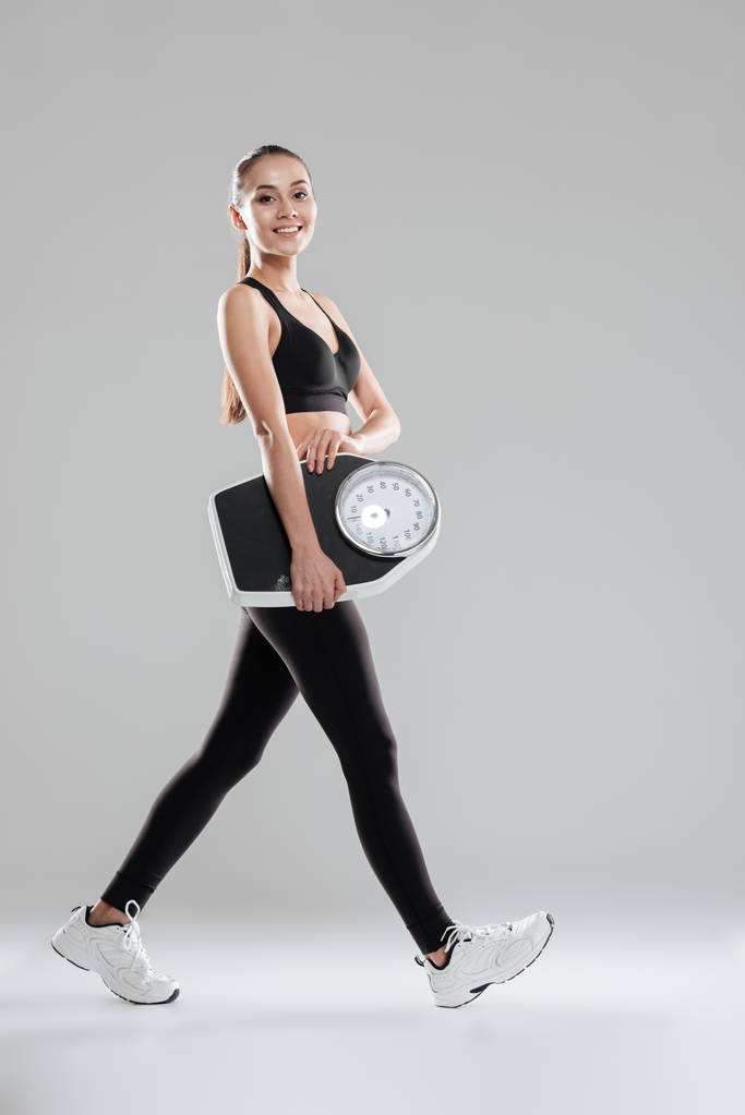 Boldog aranyos fiatal nő sportoló séta és a gazdaság mérési skála - Fotó, kép