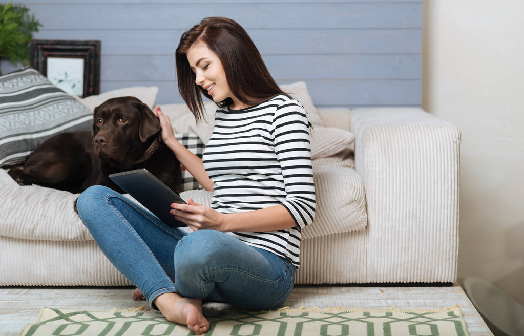 Mujer joven interesada leyendo un libro con su mascota
 - Foto, imagen