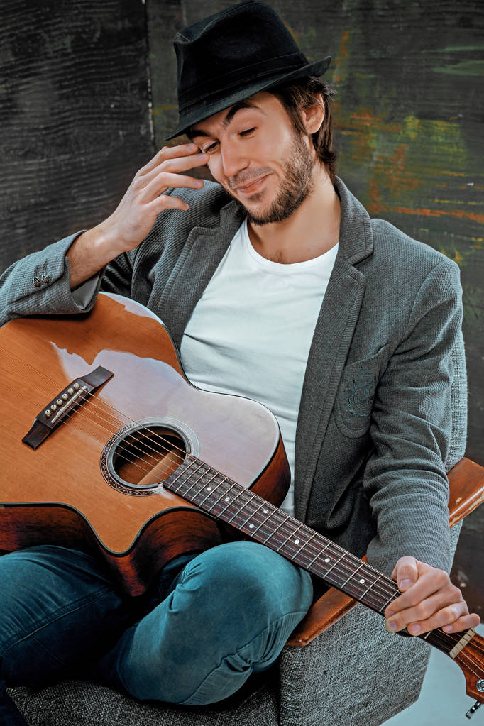 Cool guy assis avec guitare sur fond gris
 - Photo, image