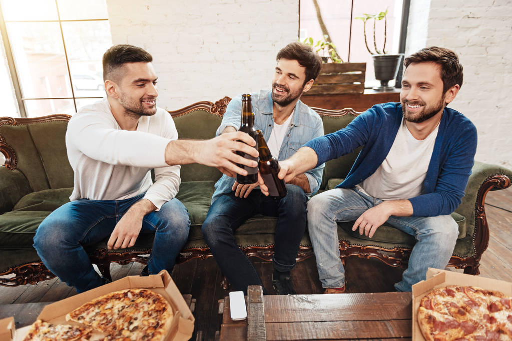 Positiiviset iloiset miehet nostamassa olutpulloja paahtoleipää varten
 - Valokuva, kuva