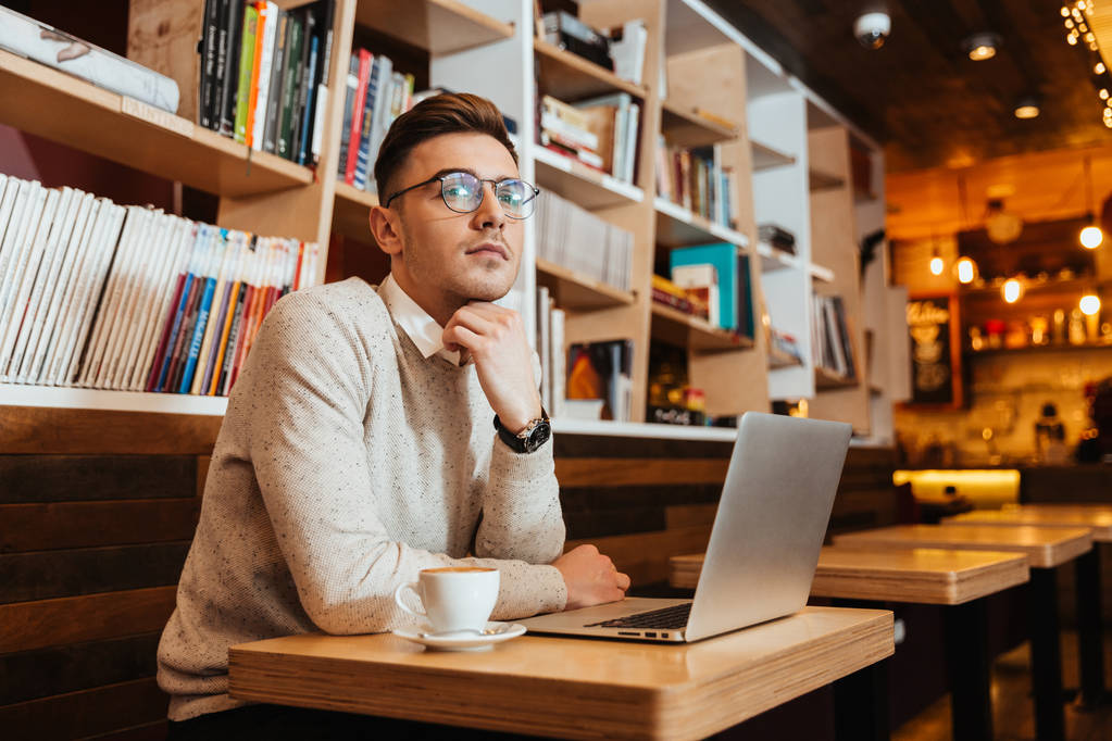 Красивый мужчина сидит в кафе с ноутбуком
 - Фото, изображение