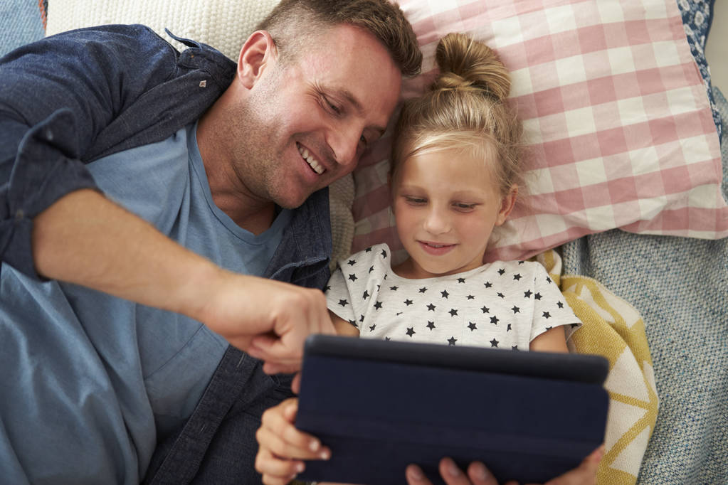 Pai e filha deitado com Tablet Digital
 - Foto, Imagem