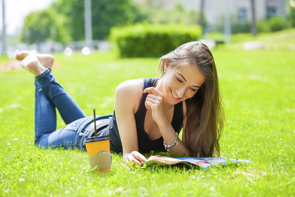若い女性の雑誌草の上に横たわって読書 - 写真・画像