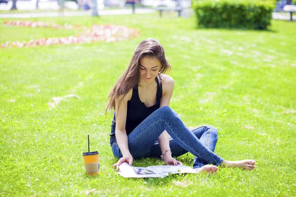 Młoda piękna kobieta siedzi w parku lato - Zdjęcie, obraz
