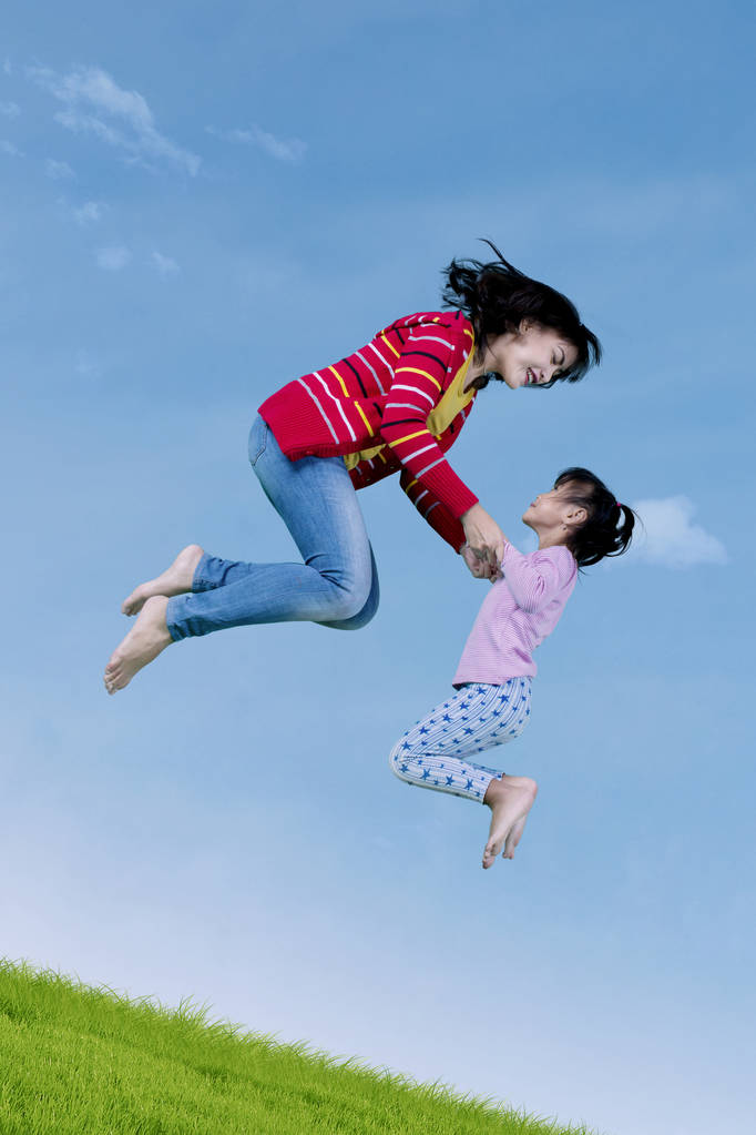 小さな女の子とお母さんが一緒に跳躍  - 写真・画像