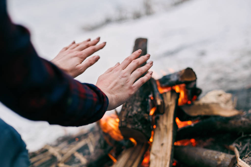 Meisje verwarmt handen in de buurt van een brand in de winter - Foto, afbeelding