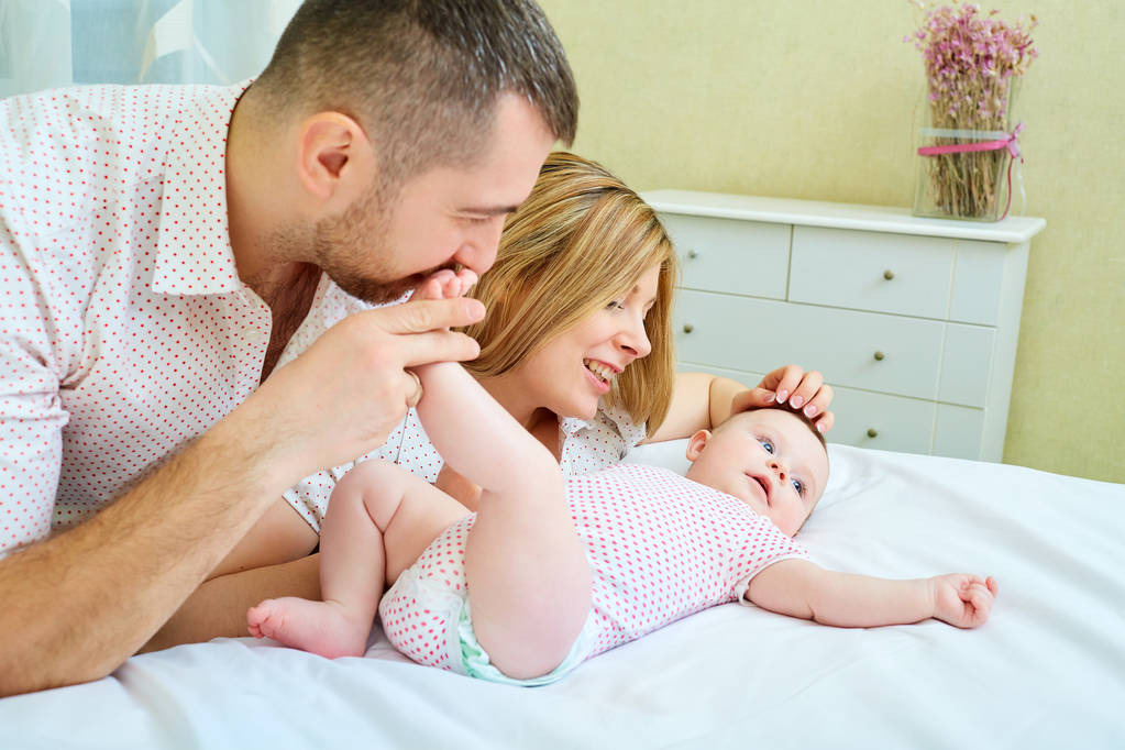 Bebé con mamá y papá sonriendo ríe en la habitación
 - Foto, imagen