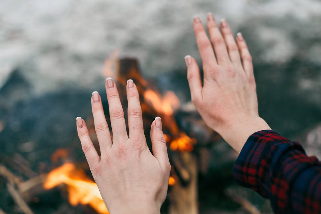 Dziewczyna ogrzewa ręce w pobliżu pożar w zimie - Zdjęcie, obraz
