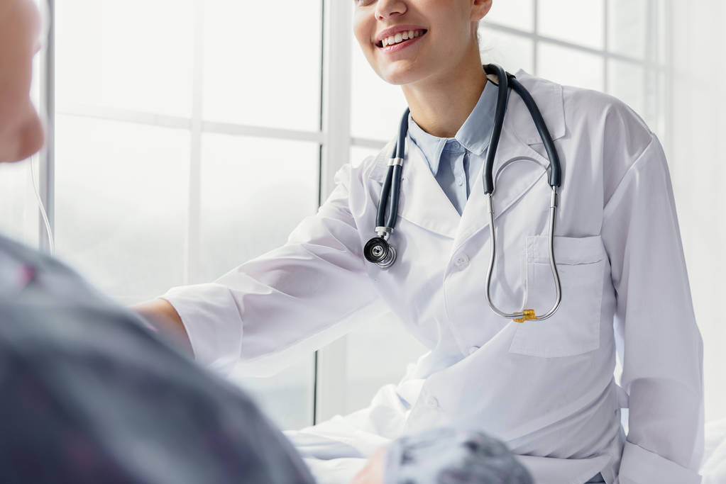 Χαμογελώντας γιατρός εξέταση πελάτη στο διαμέρισμα της κλινικής - Φωτογραφία, εικόνα