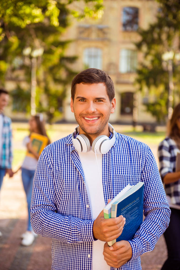 Giovane studente bello sorridente con libri in piedi vicino all'università
 - Foto, immagini