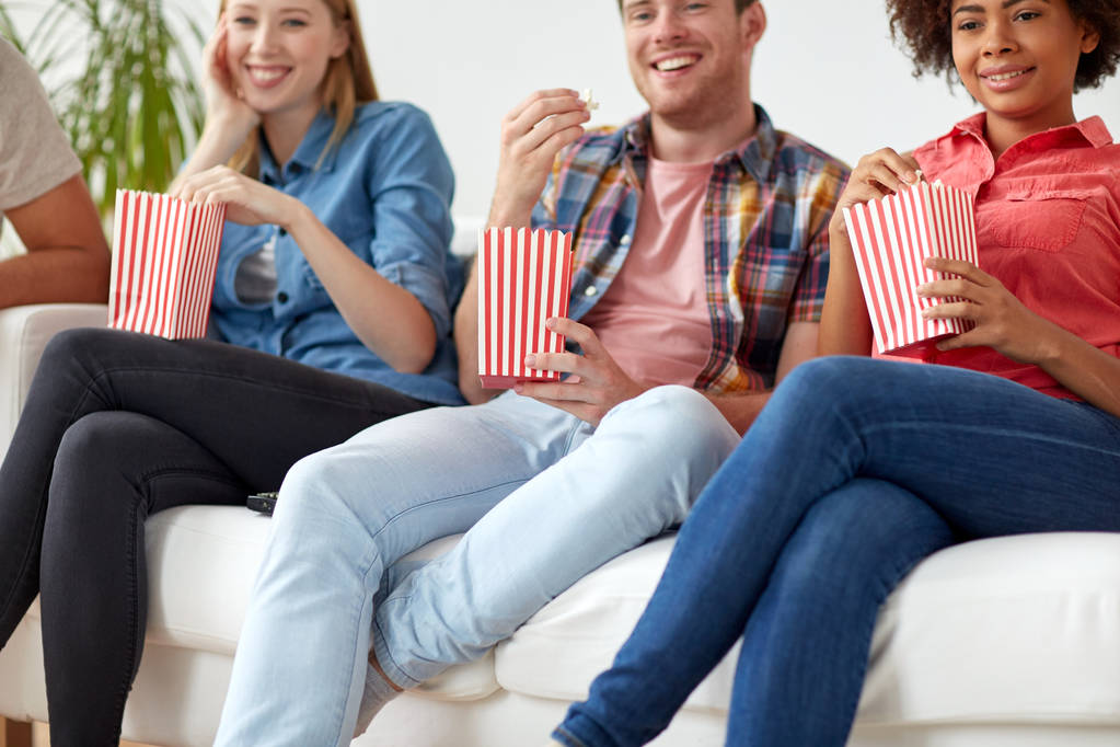 close up of happy friends eating popcorn at home - Photo, Image