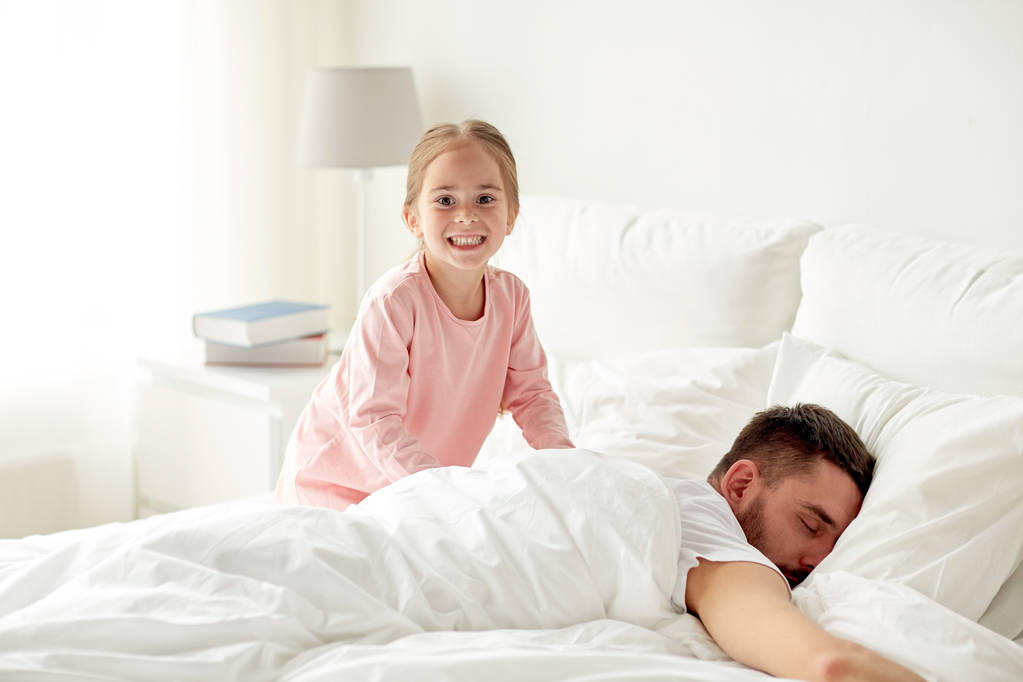 маленька дівчинка розбуджує свого батька в ліжку
 - Фото, зображення