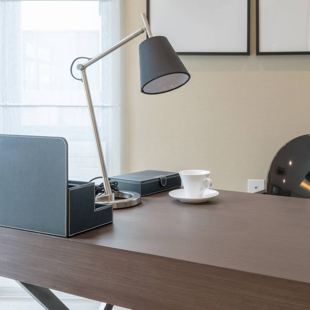 mesa de madeira com lâmpada de leitura e xícara de chá no interior moderno da sala de trabalho
 - Foto, Imagem