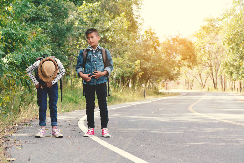 Gelukkige Aziatische kinderen rugzak op de weg en bos achtergrond - Foto, afbeelding