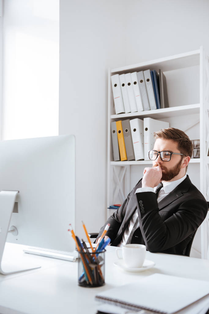 Atraktivní mladý vousatý podnikatel sedí v kanceláři - Fotografie, Obrázek