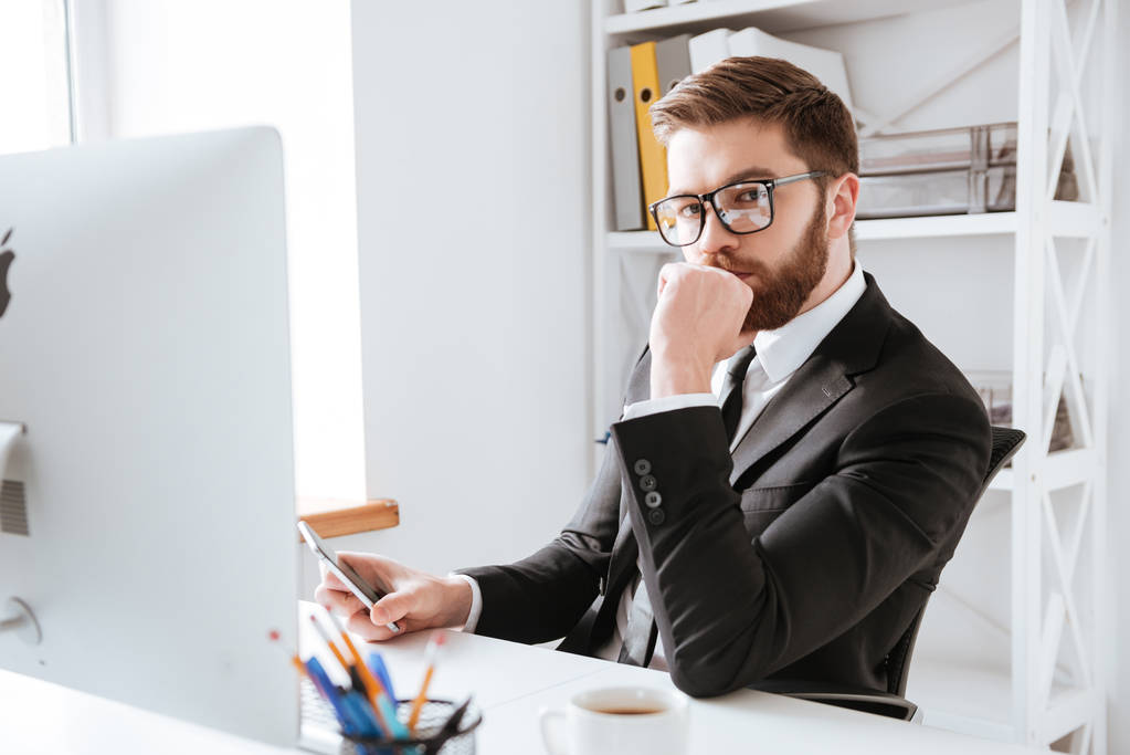 Концентрированный молодой бородатый бизнесмен с помощью компьютера
 - Фото, изображение