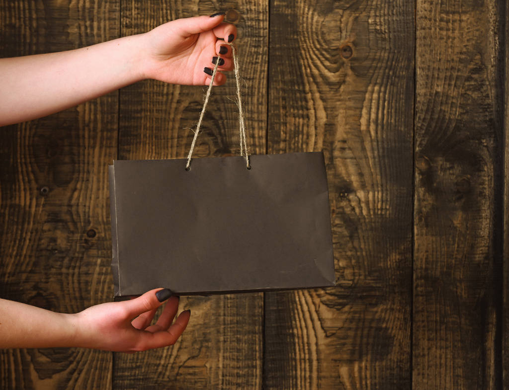 sac à provisions noir dans les mains féminines sur fond en bois
 - Photo, image