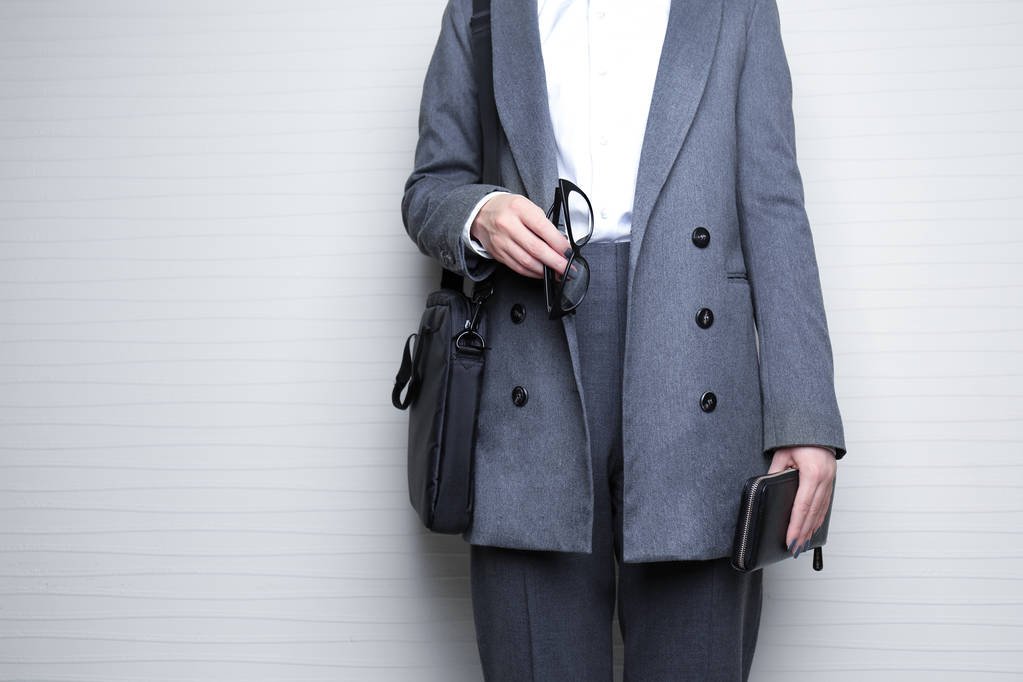 Концепция моды. Деловая женщина держит черный кошелек на светлом фоне, крупным планом
 - Фото, изображение
