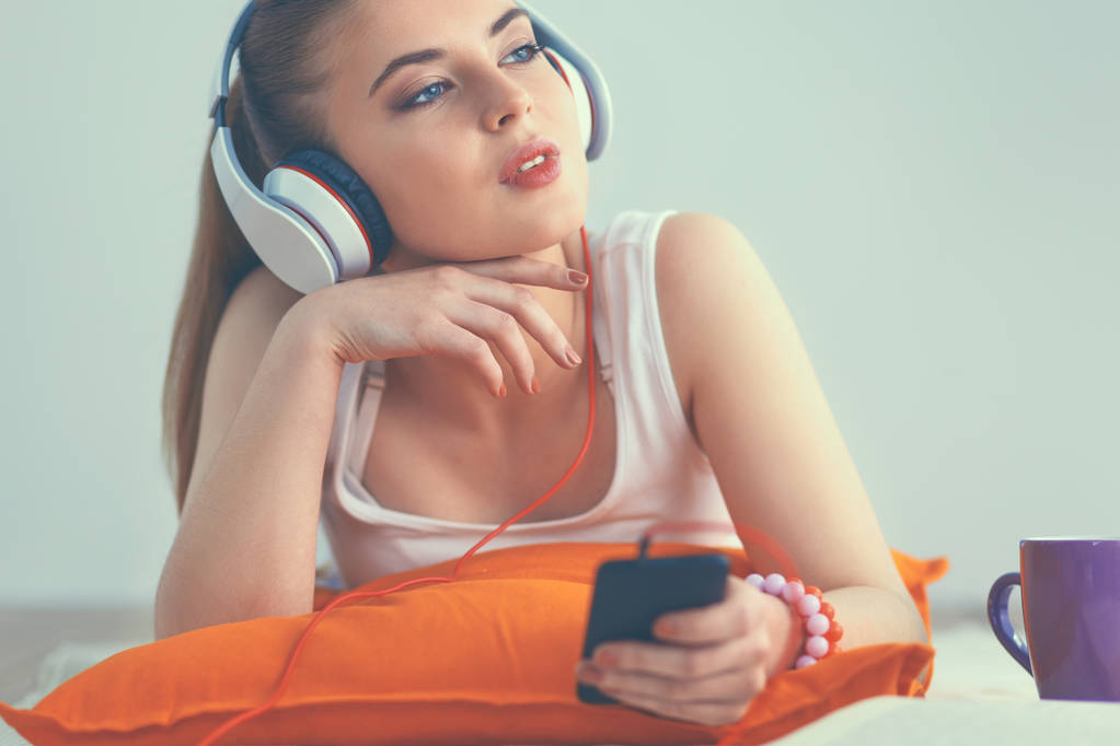Young woman lying on floor and listen to music - Photo, Image