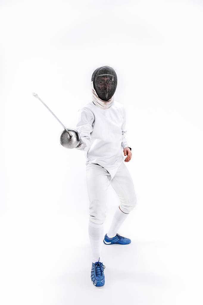 Man wearing fencing suit practicing with sword against gray - Photo, Image