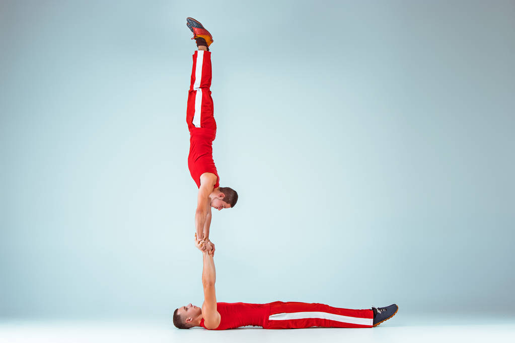 Les deux hommes acrobatiques gymnastique caucasiens sur la pose d'équilibre
 - Photo, image