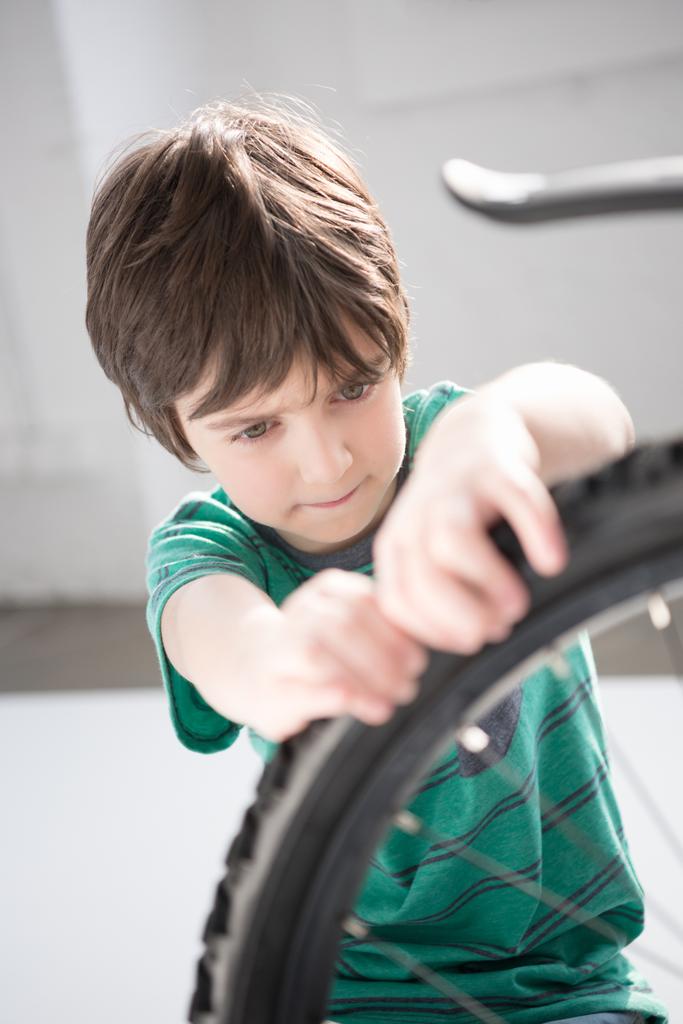 Menino verificando pneu de bicicleta
 - Foto, Imagem