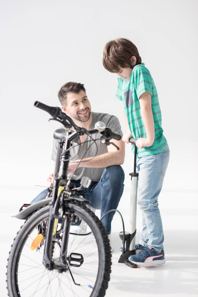 Isä ja poika täyttämässä polkupyörän rengasta
 - Valokuva, kuva