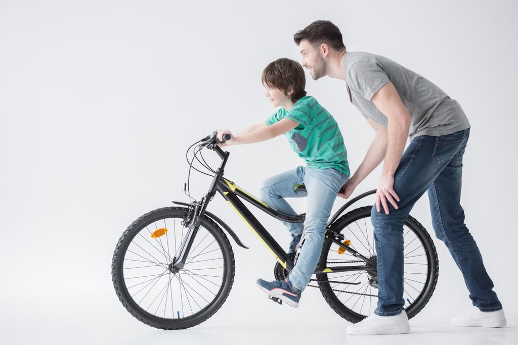 father helping son to ride bicycle - Photo, Image