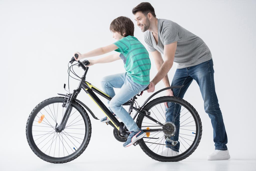 father helping son to ride bicycle - Photo, Image