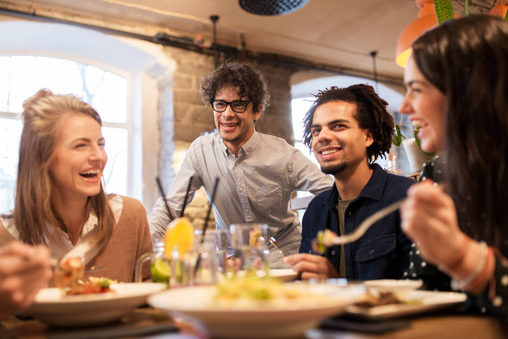 счастливые друзья едят и пьют в ресторане
 - Фото, изображение