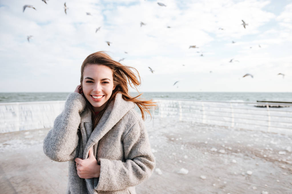 Onnellinen nainen hymyilee ja kävelee laiturilla talvella
 - Valokuva, kuva