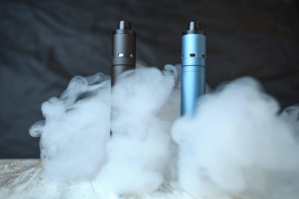 Elektronik cigaretts ve masanın üstünde buhar bulutu. Mekanik mod. Biter. - Fotoğraf, Görsel