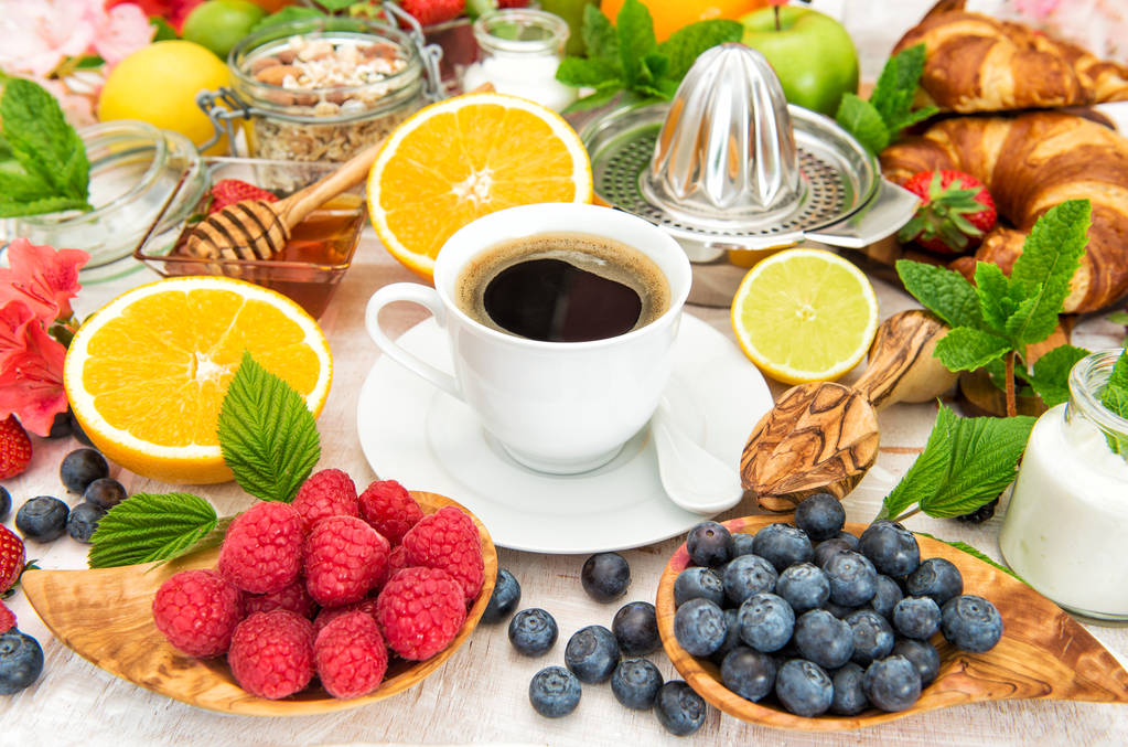 Reggeli kávé, croissant, müzli friss gyümölcsök, bogyós gyümölcsök - Fotó, kép