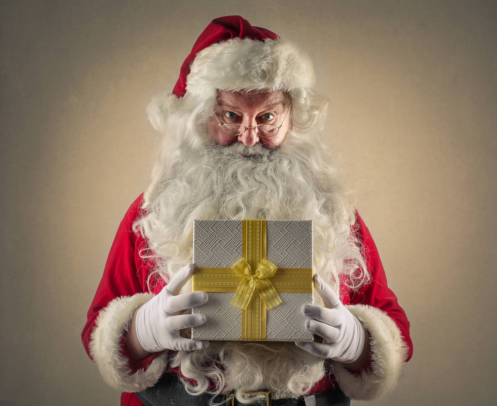 Santa sosteniendo un regalo
 - Foto, Imagen